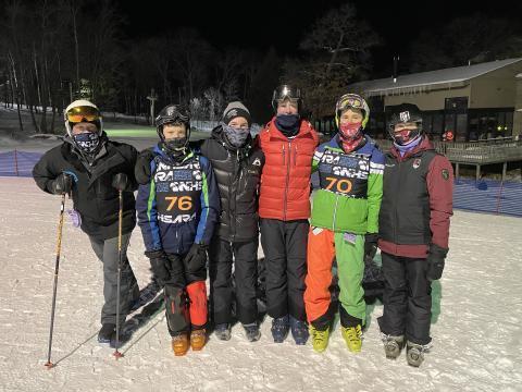 Members of the boys' ski team link arms on the ski slope as they pose for a picture.  