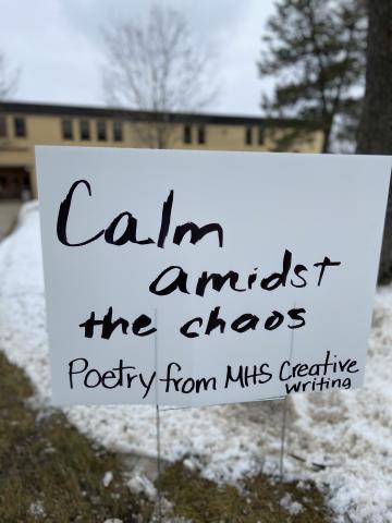 Poetry is displayed on a yard sign. 